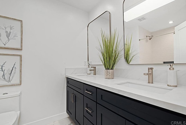 bathroom with visible vents, double vanity, a sink, and toilet