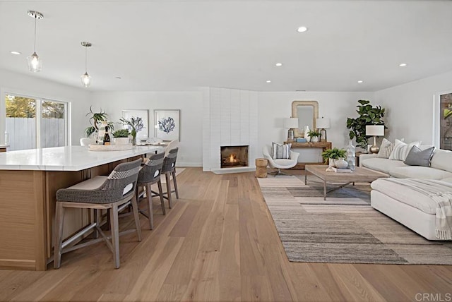 living room featuring recessed lighting, a fireplace, and light wood finished floors