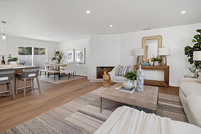 living area featuring a large fireplace, recessed lighting, visible vents, and light wood-style floors