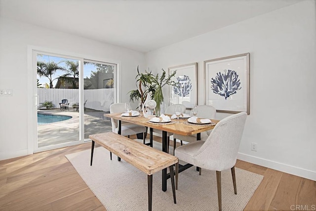 dining space with baseboards and light wood-style floors