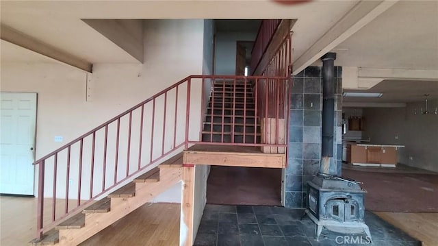 stairs featuring beam ceiling and a wood stove