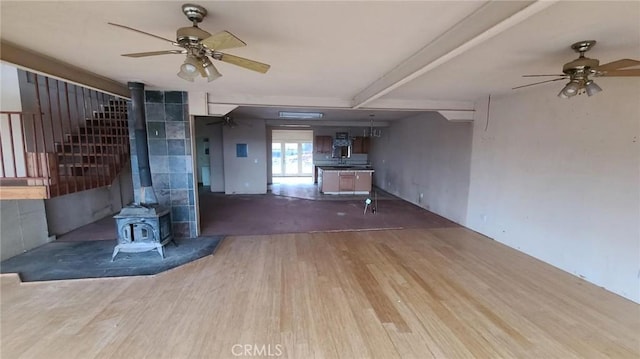 unfurnished living room with hardwood / wood-style floors, ceiling fan, and a wood stove