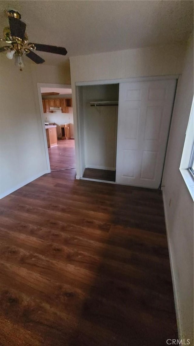 unfurnished bedroom with dark hardwood / wood-style floors, ceiling fan, and a closet