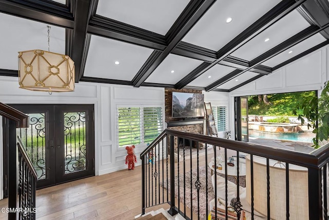 entrance foyer featuring beamed ceiling, ornamental molding, coffered ceiling, light hardwood / wood-style floors, and french doors