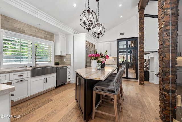 kitchen featuring pendant lighting, sink, appliances with stainless steel finishes, white cabinetry, and a center island