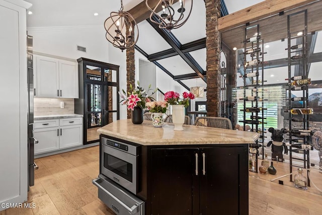 kitchen with stainless steel microwave, a center island, light hardwood / wood-style floors, and white cabinets