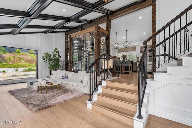 staircase featuring beamed ceiling, a wealth of natural light, coffered ceiling, and hardwood / wood-style floors