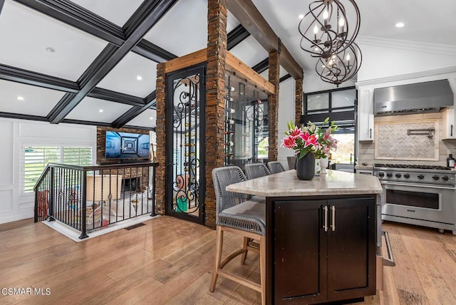 dining space with crown molding, light hardwood / wood-style flooring, an inviting chandelier, coffered ceiling, and lofted ceiling with beams