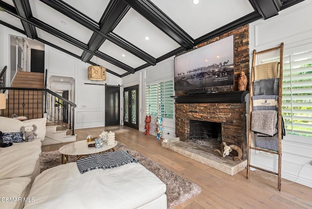 living room with a healthy amount of sunlight, coffered ceiling, light hardwood / wood-style floors, and beam ceiling