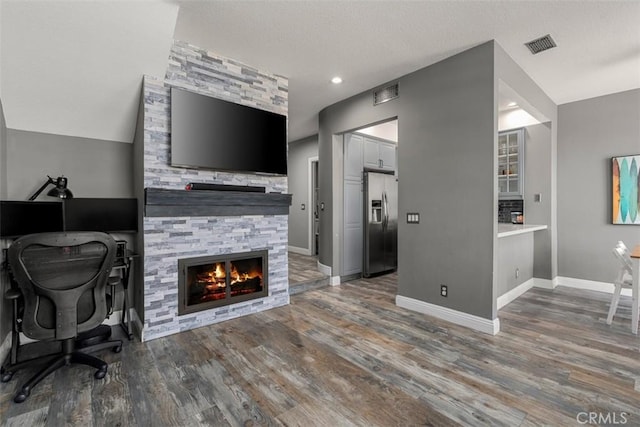 office space with dark hardwood / wood-style flooring and a stone fireplace