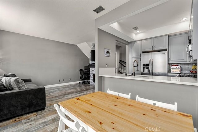 kitchen with sink, tasteful backsplash, wood-type flooring, appliances with stainless steel finishes, and gray cabinets