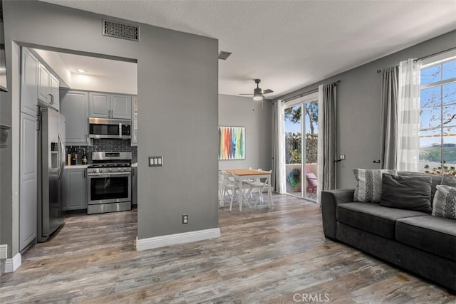 living room with ceiling fan, light hardwood / wood-style floors, and a healthy amount of sunlight