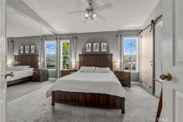 bedroom featuring multiple windows, vaulted ceiling, a barn door, and light colored carpet