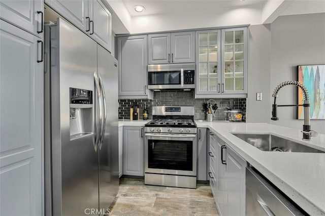 kitchen with tasteful backsplash, sink, gray cabinets, and stainless steel appliances