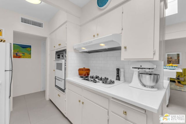 kitchen with light tile patterned floors, white appliances, decorative backsplash, and white cabinets