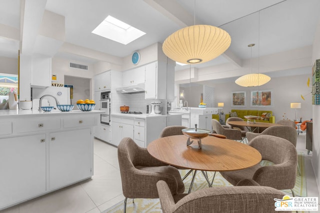 kitchen featuring pendant lighting, light tile patterned floors, tasteful backsplash, white cabinets, and kitchen peninsula