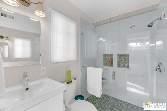 bathroom featuring vanity, toilet, an enclosed shower, and a wealth of natural light