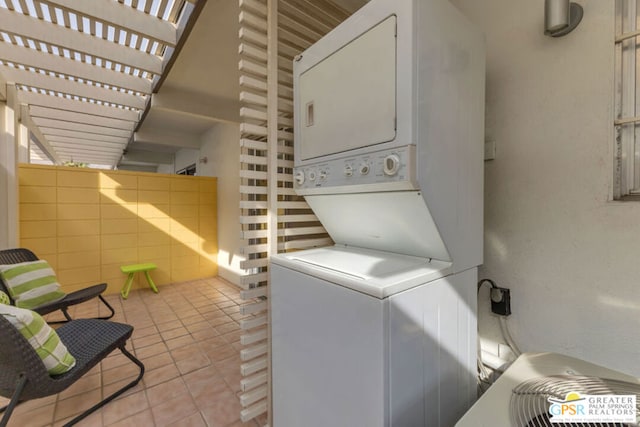 clothes washing area with stacked washing maching and dryer and light tile patterned floors