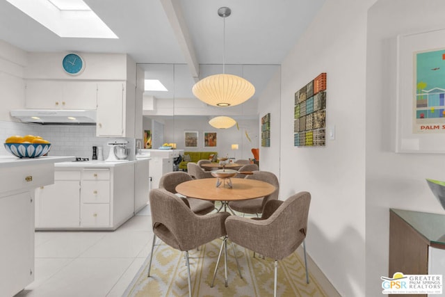 tiled dining room with beamed ceiling and a skylight