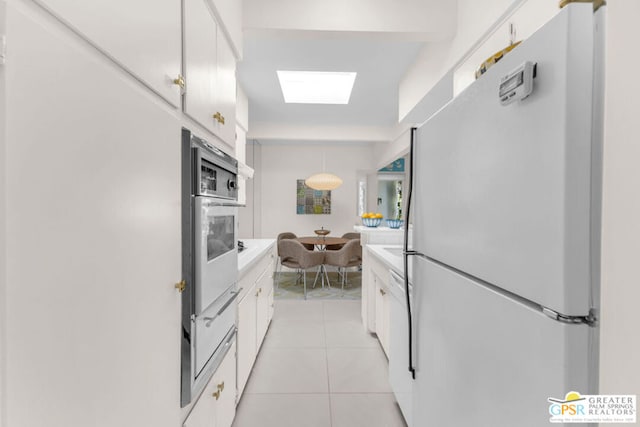 kitchen featuring light tile patterned floors, white appliances, white cabinetry, hanging light fixtures, and a skylight