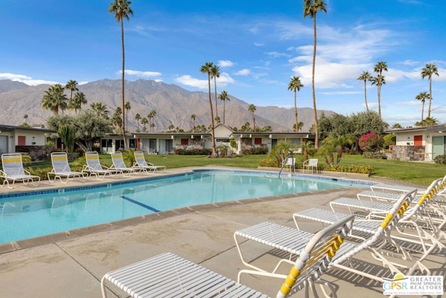 view of swimming pool with a yard, a mountain view, and a patio