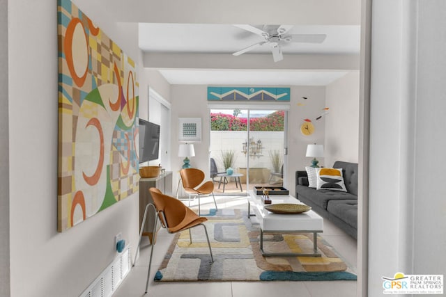 living area featuring tile patterned flooring, beamed ceiling, and ceiling fan