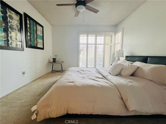 carpeted bedroom featuring ceiling fan and a textured ceiling