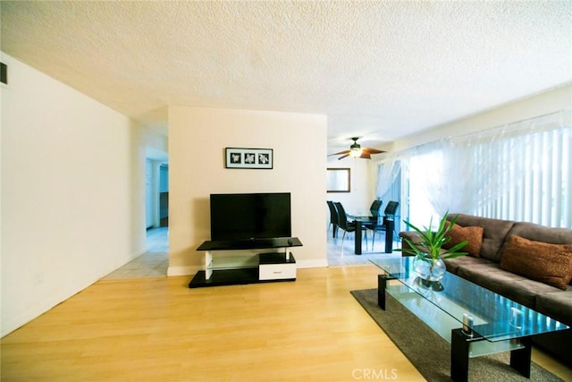 living room with ceiling fan, wood-type flooring, and a textured ceiling