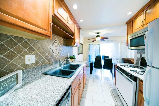 kitchen featuring light tile patterned flooring, sink, ceiling fan, stainless steel appliances, and decorative backsplash