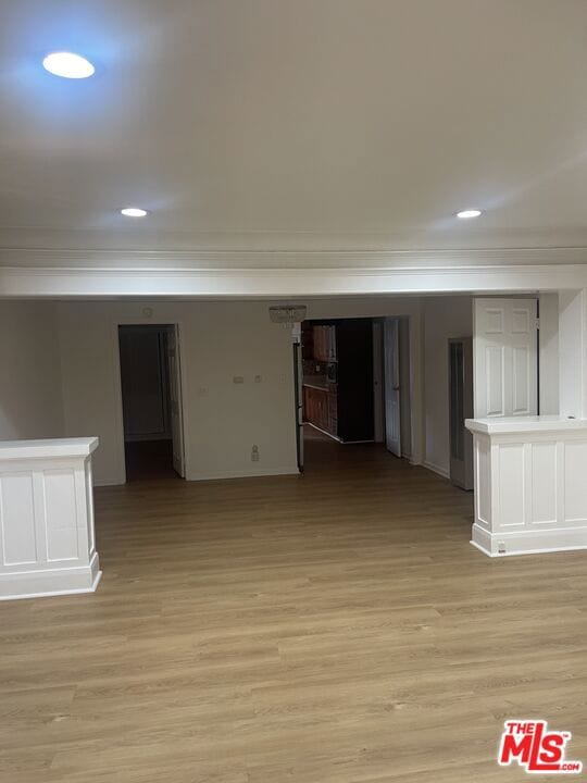 spare room with ornamental molding and light wood-type flooring