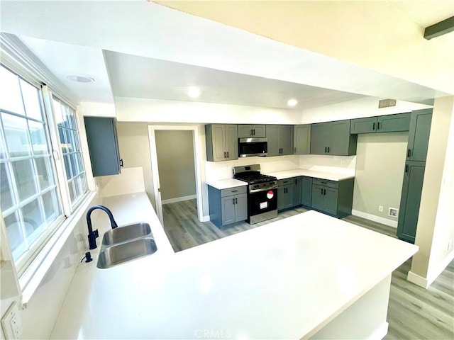 kitchen featuring appliances with stainless steel finishes, light hardwood / wood-style floors, sink, and kitchen peninsula