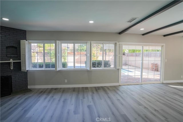 unfurnished living room featuring beam ceiling, a fireplace, and light hardwood / wood-style flooring