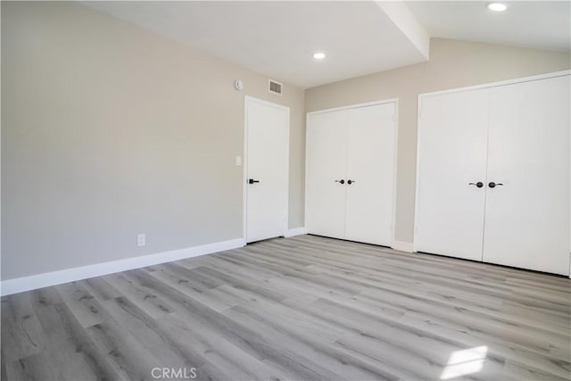 unfurnished bedroom with lofted ceiling and light hardwood / wood-style floors