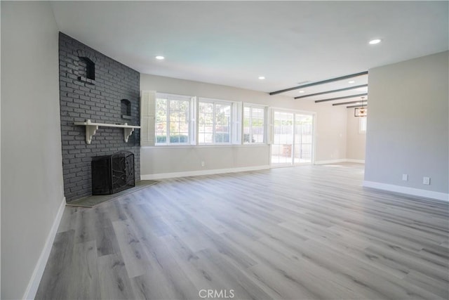 unfurnished living room featuring a brick fireplace and light hardwood / wood-style floors