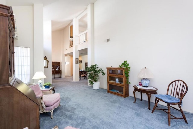 living area featuring a towering ceiling and carpet floors