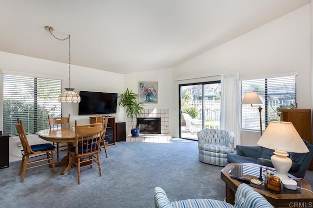 living room featuring a tile fireplace, lofted ceiling, plenty of natural light, and carpet flooring