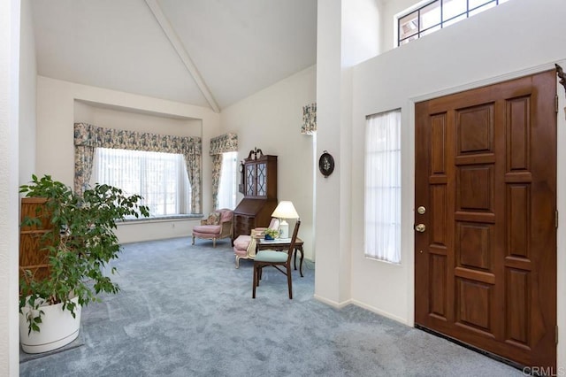 carpeted foyer entrance featuring high vaulted ceiling