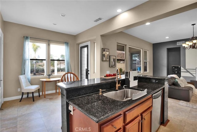 kitchen featuring sink, dishwasher, a center island with sink, decorative light fixtures, and dark stone counters