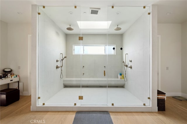 bathroom with walk in shower, a skylight, and hardwood / wood-style floors