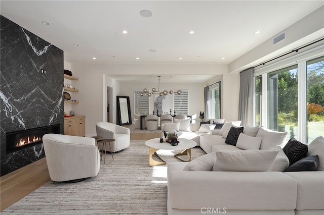 living room featuring light wood-type flooring, an inviting chandelier, and a fireplace