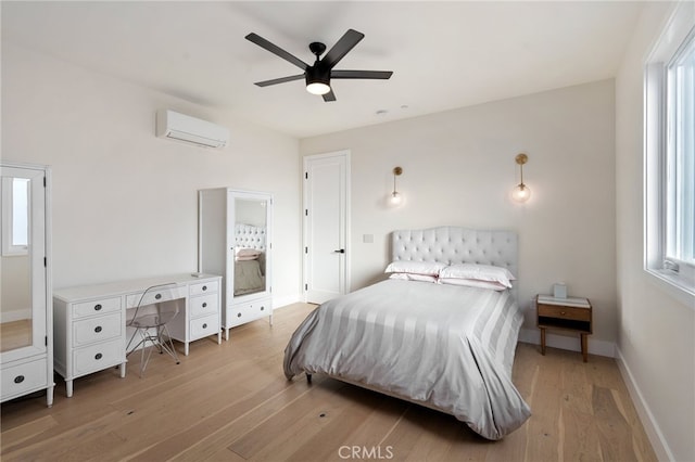 bedroom featuring a wall unit AC, ceiling fan, and light wood-type flooring