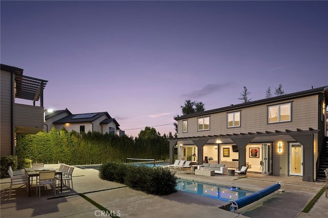 pool at dusk featuring a pergola, an outdoor hangout area, and a patio area