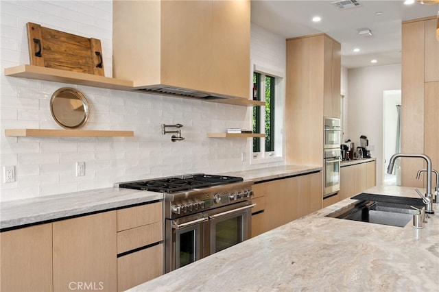 kitchen with stainless steel appliances, light stone countertops, sink, and custom exhaust hood