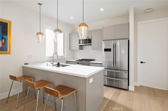 kitchen with sink, appliances with stainless steel finishes, a kitchen breakfast bar, gray cabinets, and kitchen peninsula