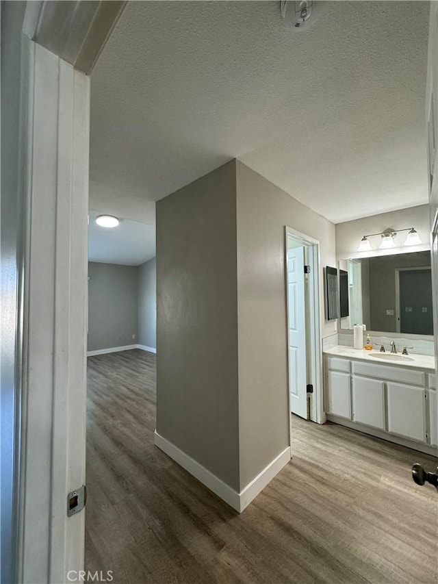 hall with sink, hardwood / wood-style floors, and a textured ceiling