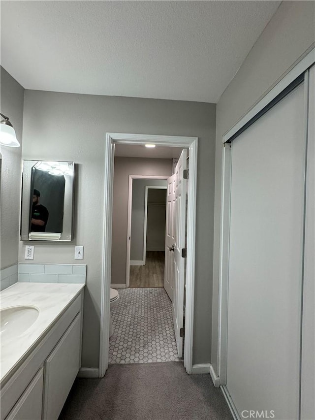 bathroom featuring vanity, a textured ceiling, and toilet