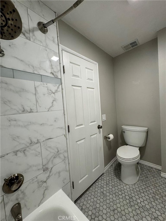 bathroom with tiled shower / bath combo and toilet