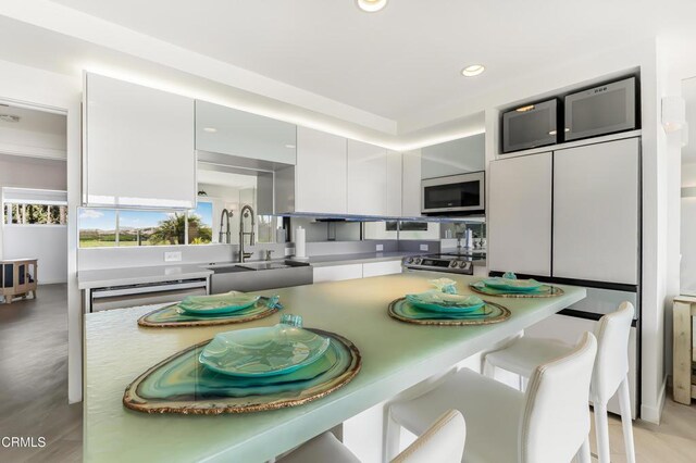 kitchen featuring white cabinetry, stove, a breakfast bar, and sink