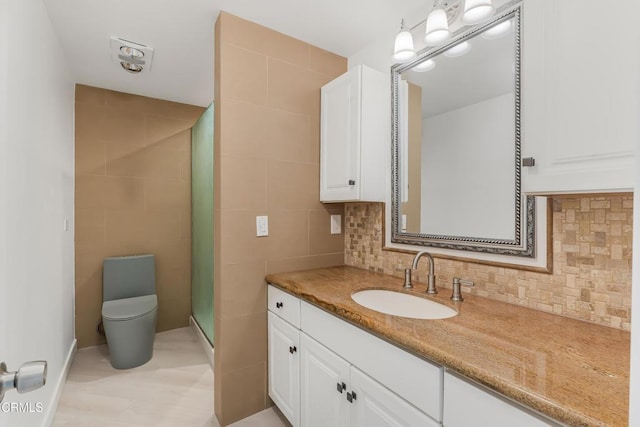 bathroom with tile walls, tasteful backsplash, vanity, toilet, and walk in shower