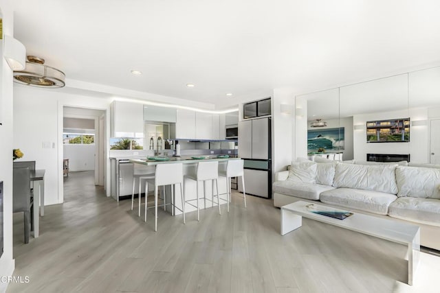 kitchen with white cabinetry, a center island, fridge, a kitchen breakfast bar, and light hardwood / wood-style floors